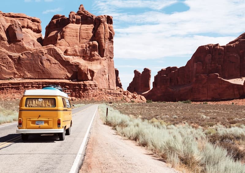 A camper van rolling through red-rock canyons