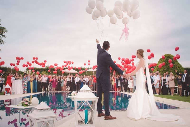 Newlyweds releasing balloons over a poolside crowd